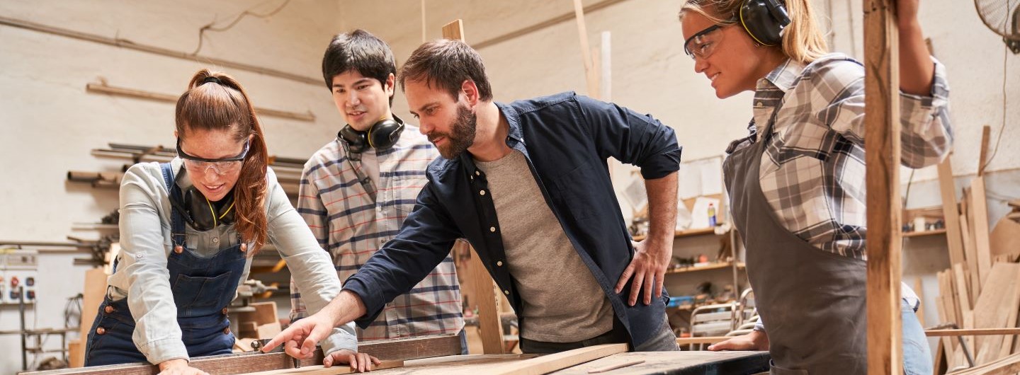 Ausbildung der Ausbilder: Schreinerei Lehrlinge mit Ausbilder an der Kreissäge
