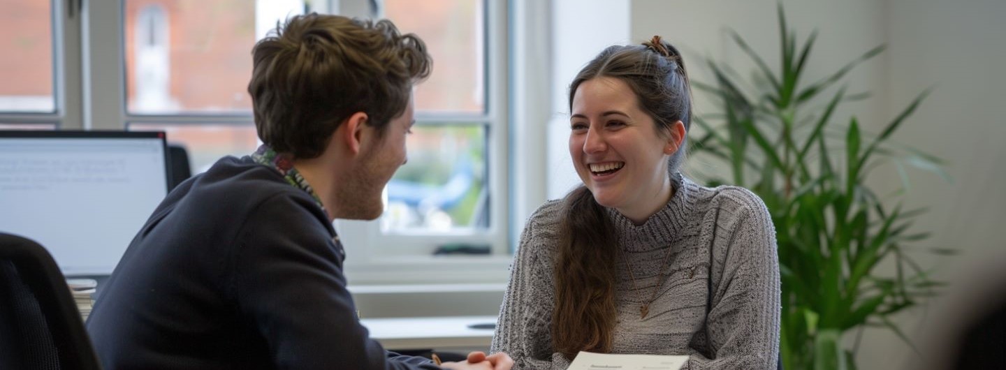 Beziehungskompetenz und Menschenkenntnis Weiterbildung: Zwei Kollegen lachen und unterhalten sich in einem Büro