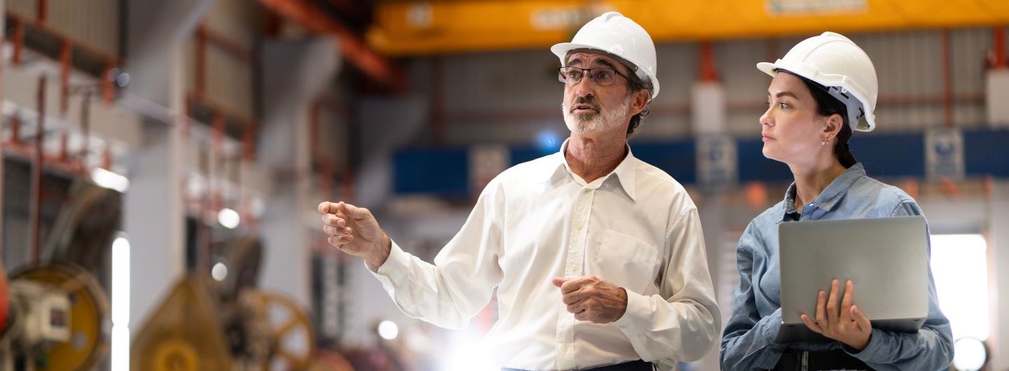 Engineering Management Studium: eine Engineering Managerin bespricht sich mit einem Kollegen in einer Produktionshalle