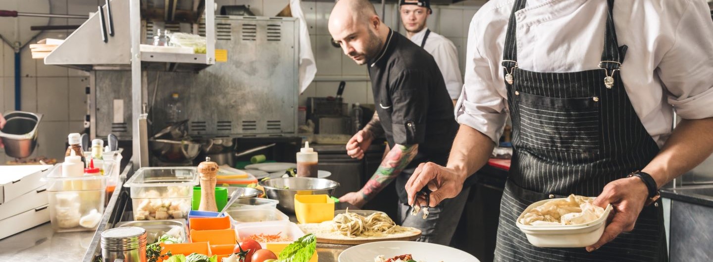 Drei Köche kochen in einer Gastronomieküche