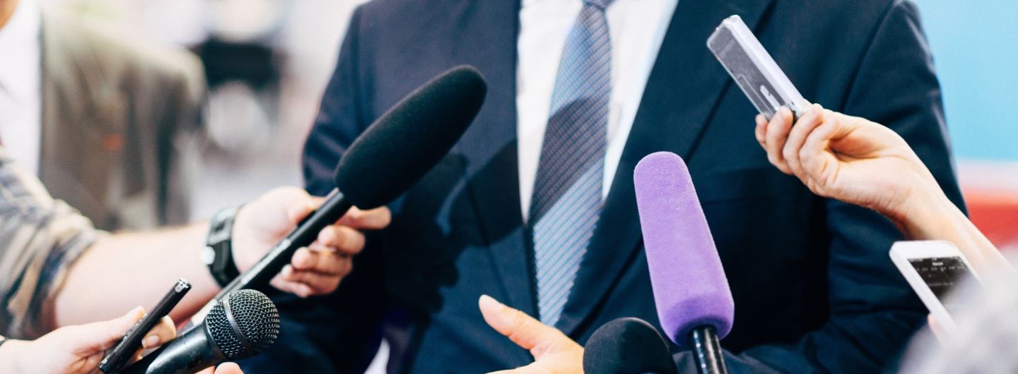 PR Mann wird von mehreren Reportern interviewt