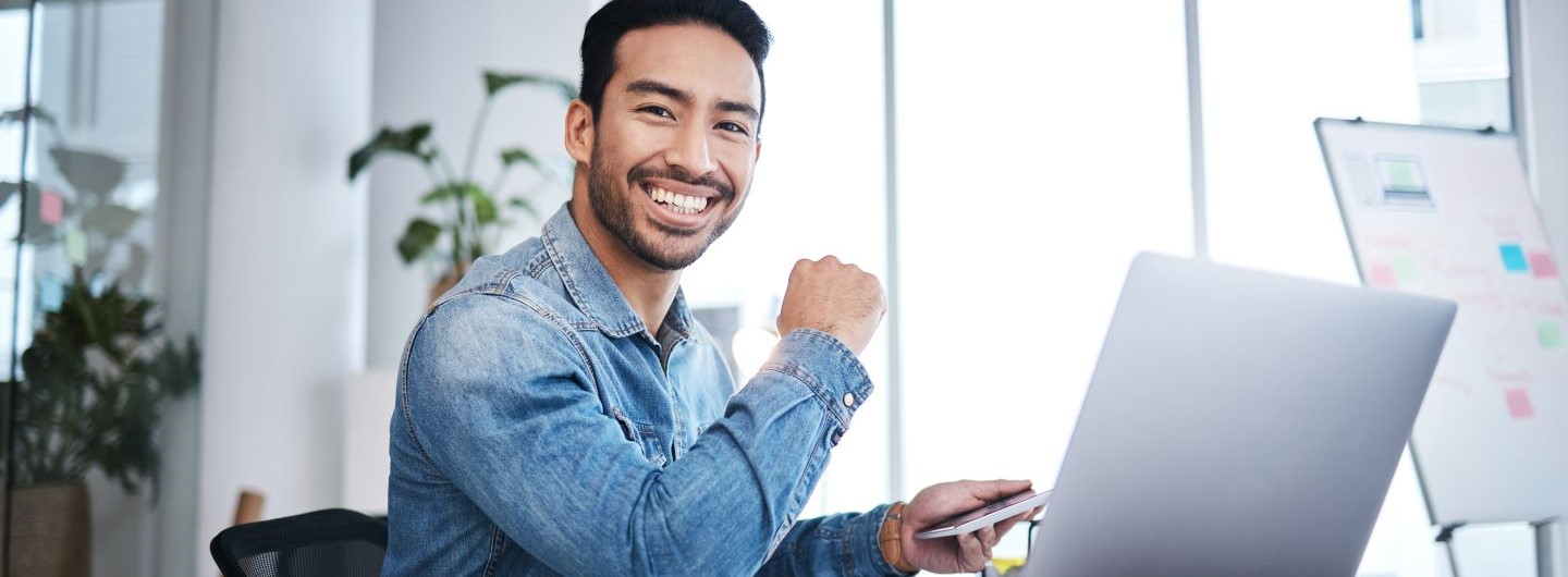 SAP-Key-User Weiterbildung: Ein junger SAP Key User sitzt lächelnd am Laptop
