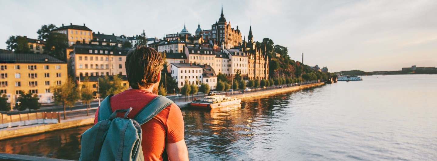 Mann mit Rucksack besucht die Stadt Stockholm und genießt die Aussicht auf einer Brücke