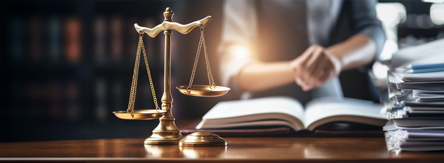 Sozialrecht Studium: eine Anwältin sichtet Vertragspapiere auf Holzschreibtisch in Büro, im Vordergrund steht eine Messingwaage
