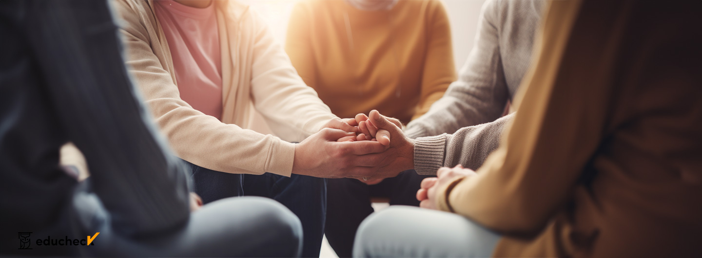 Suchtberatung Ausbildung: eine Gruppe von Menschen, die in einem Kreis sitzen und sich an den Händen halten und sich damit gegenseitig unterstützen in einer Therapiesitzung