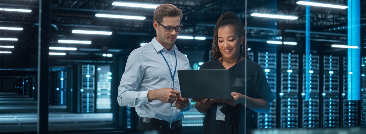 Technische Informatik Studium: Zwei technische Informatiker beraten sich am Laptop vor einem Serverraum