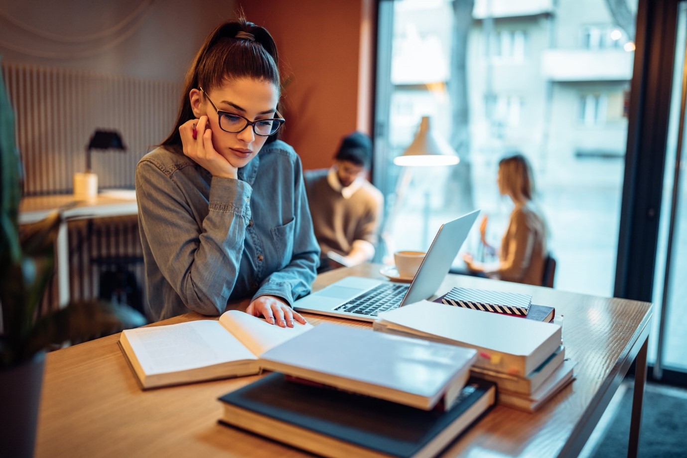 Ein junges Mädchen lernt für das Abitur mit Laptop und Büchern