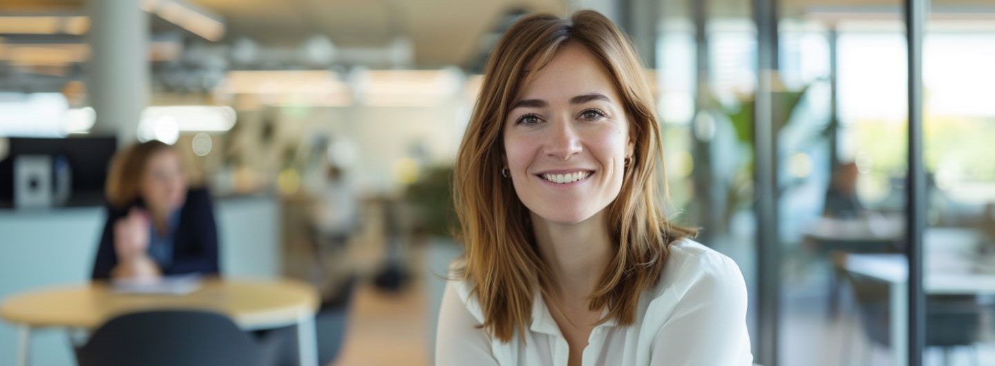eine Personal Mitarbeiter sitzt in einem modernen Büro und lächelt in die Kamera